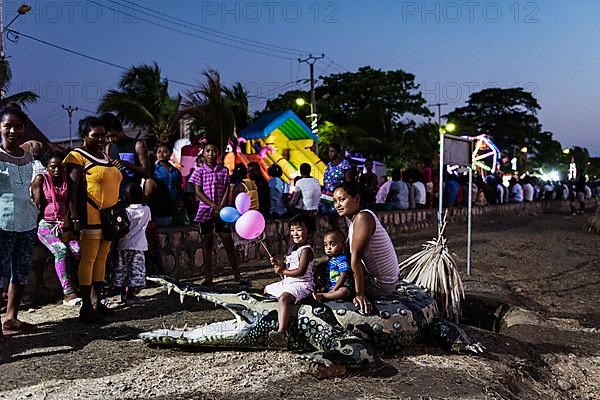 Mother and two children posing on artificial crocodile, dummy