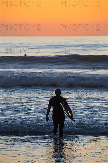 Surfer in backlight in the ocean of Del Mar, California