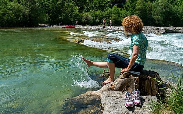 Hiker cools her feet in the river Isar, Bad Toelz