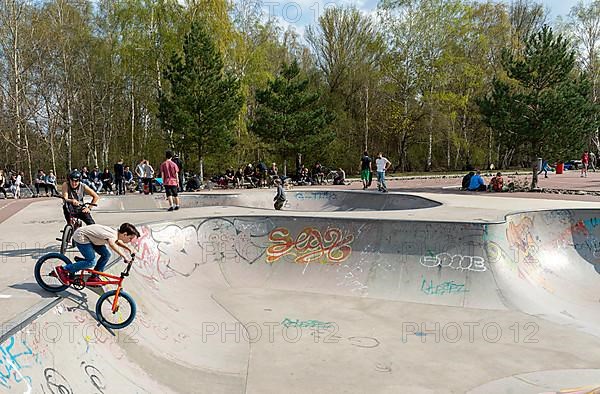 Skateboarders and cyclists at a skate pool in the Park am Gleisdreieck in Berlin-Mitte, Berlin