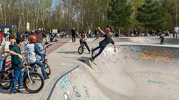 Skateboarders and cyclists at a skate pool in the Park am Gleisdreieck in Berlin-Mitte, Berlin