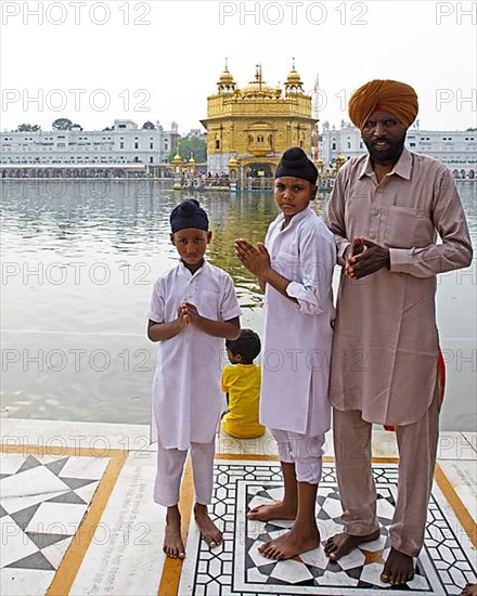 Indian Sikhs in white suits and bare feet at the Hari Mandir or Golden Temple, Amritsar