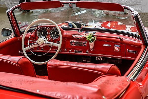 View into interior of convertible classic car Mercedes SL 190 with red leather, white spoke steering wheel