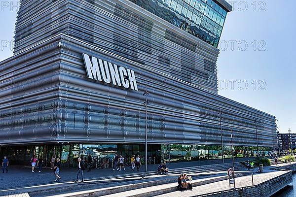 Pedestrians in front of Munch Museum, facade with wave-shaped panels made of recycled aluminium and glass