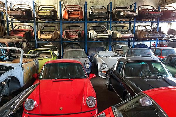 Oversized shelf spare parts storage in workshop for Porsche classic car not restored bodywork bodies of historic classic sports car classic car Porsche 911, in foreground restored Porsche 911