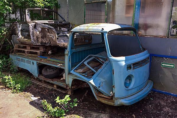 Rusty body from wreck of historic classic sports car classic car Porsche 911 lies on loading area of rusty wreck of VW Bulli t2 transporter lies in backyard, Germany