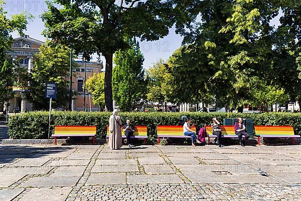 Street scene, men and woman on benches in rainbow colours