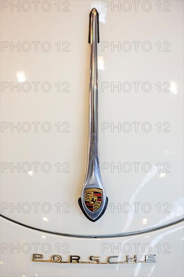 Detail of boot lid of historic classic car Porsche 356 from 50s 60s with metal bracket teardrop shape with Porsche logo emblem, underneath Porsche lettering