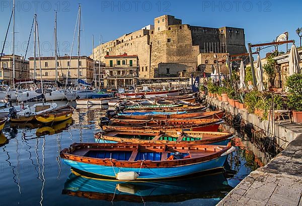 Fishing and boating port of Santa Lucia with Castel dell Ovo in early morning sun, Naples