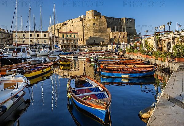 Fishing and boating port of Santa Lucia with Castel dell Ovo in early morning sun, Naples