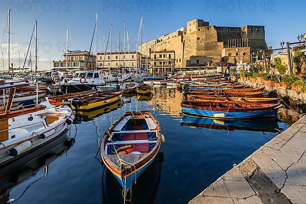 Fishing and boating port of Santa Lucia with Castel dell Ovo in early morning sun, Naples