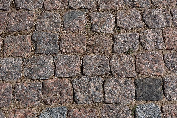 Cobblestone pavement. Texture of cobblestone road close-up. Part of the road paved with red black granite