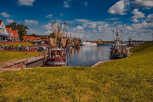 The fishing harbour in Greetsiel in sunshine and a few spring clouds in the blue sky