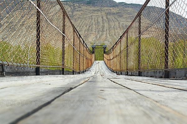 Suspension bridge over a mountain river in a gorge. Russia