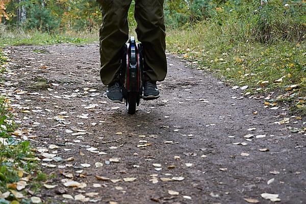 Front view of male legs on a unicycle in the forest