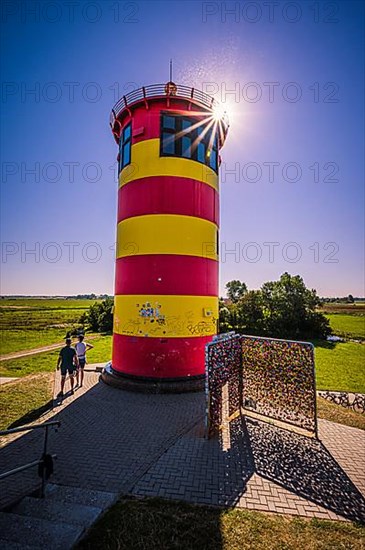 The Pilsum lighthouse on the dike in summer with a summer star near Greetsiel on the North Sea