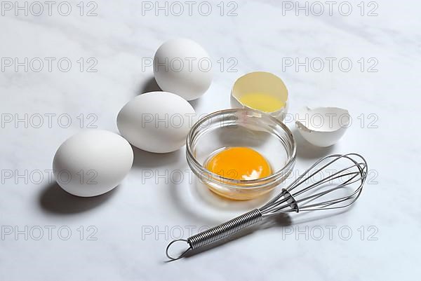 Egg yolks in small bowls and egg whites in egg shells