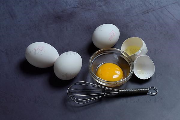 Egg yolks in small bowls and egg whites in egg shells