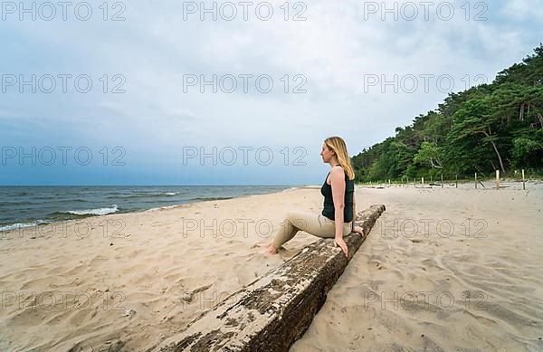 Happy woman sitting on a wooden beam at a lonely stand