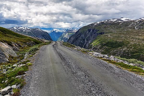 Gravel road through barren mountain landscape with remnants of snow