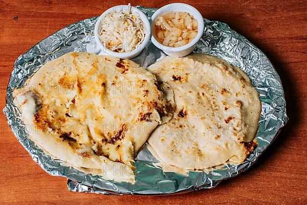 Top view of two Nicaraguan pupusas served with salad on the table. Delicious Salvadoran pupusas with melted cheese served on the table. Traditional pupusas served with salad on the table