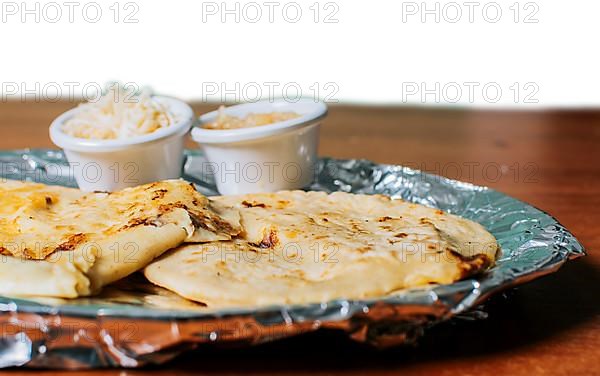 Two traditional pupusas served with salad on the table. Two Nicaraguan pupusas with salad isolated