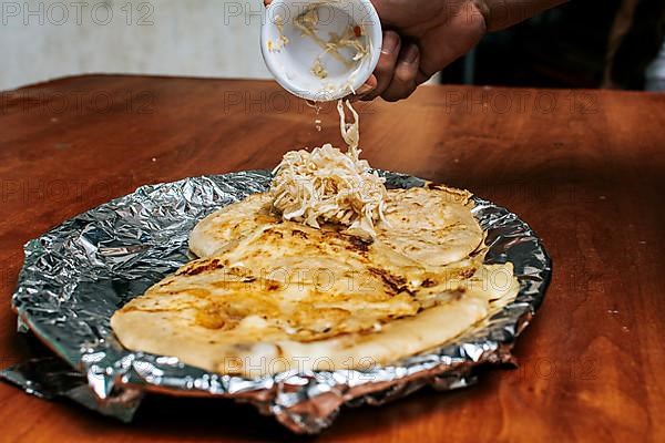 Traditional pupusas served with salad on the table. Nicaraguan pupusas with salad on aluminum foil