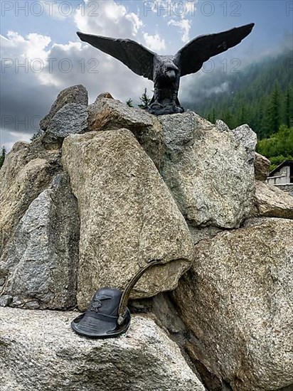 Monument to Italian mountain fighters with statue in metal of eagle golden eagle and hat with feather