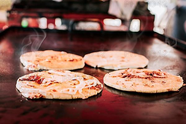 Traditional Salvadoran pupusas with melted cheese on a grill