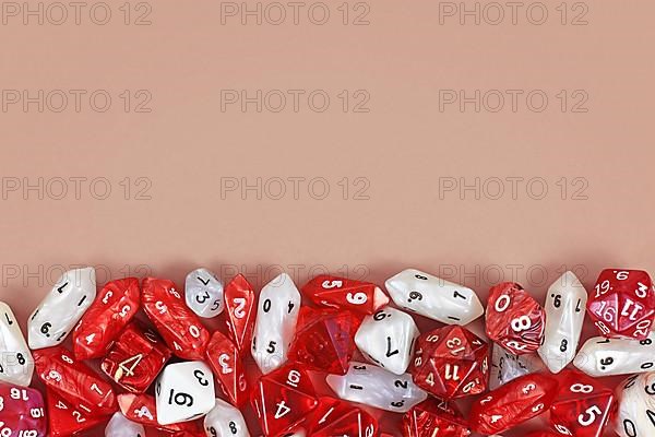 Different red roleplaying RPG dice at bottom of beige background with blank copy space