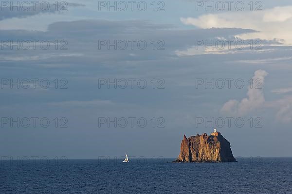Sailboat in front of the small island of Eolie with lighthouse