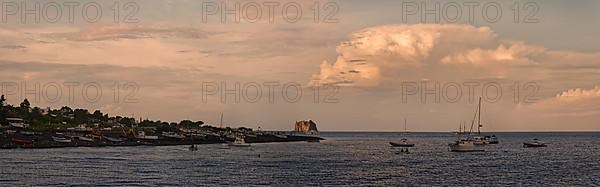 Small fishing village and harbour of San Vincenzo island and Stromboli volcano at sunset and anchored sailboats