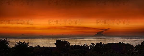 Strompoli volcano with plumes of smoke at sunset