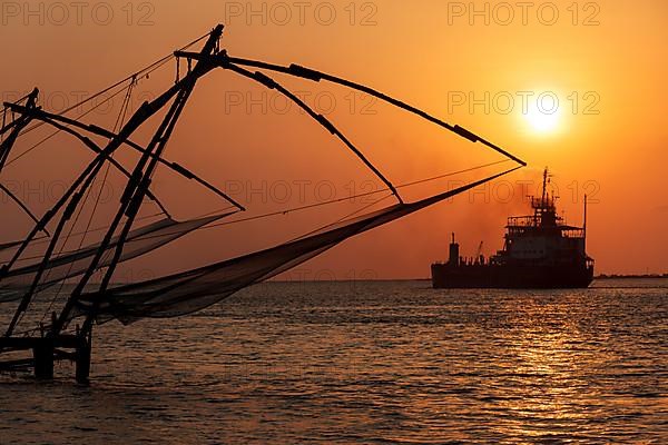 Kochi chinese fishnets on sunset and modern ship. Fort Kochin