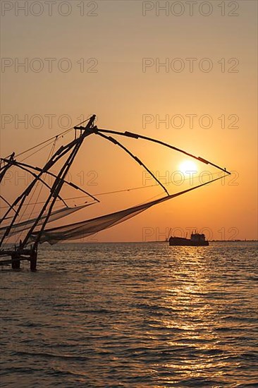 Kochi chinese fishnets on sunset and modern ship. Fort Kochin