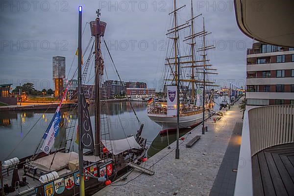 View from the balcony on the 1st floor of the Hotel Liberty into the Havenwelten in the evening with the sail training ship Deutschland