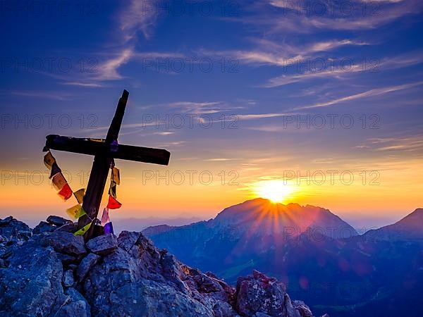 Buddhist prayer flags on the summit cross of the Kleiner Watzmann at sunrise