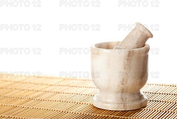Marble mortar with pestle on bamboo mat