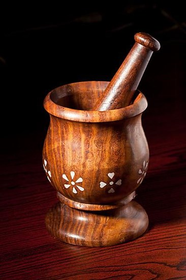 Wooden mortar and pestle on dark wood background