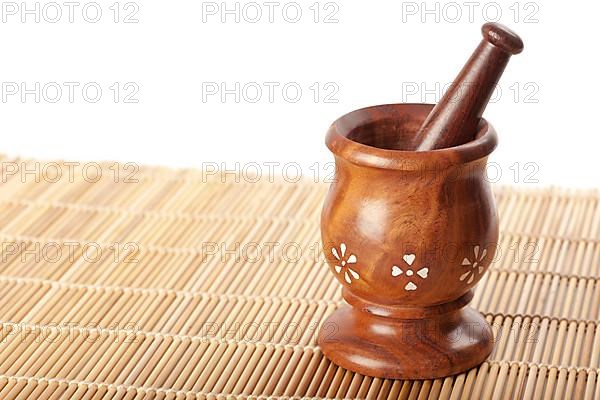 Wooden mortar with pestle on bamboo mat