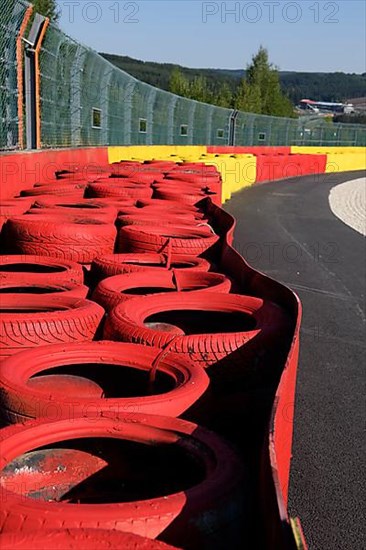 Safety measure for car racing Impact protection red yellow coloured tyre piles next to gravel bed in turn 8 of racetrack for motorsport