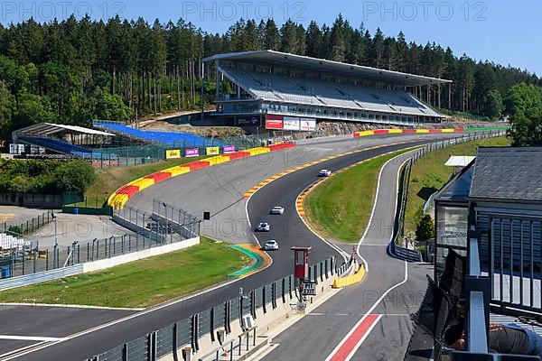 View of four racing cars racing through dangerous Eau Rouge bend on 40-metre-high Raidillon slip road of Circuit de Spa Francorchamps