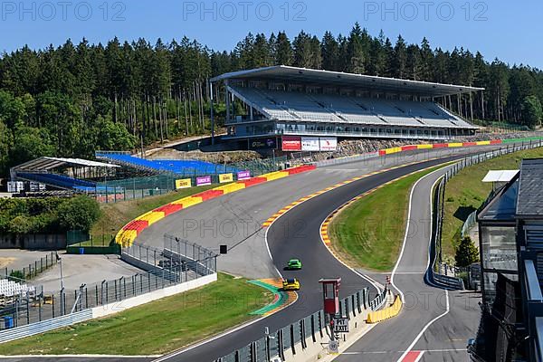 View of two Porsche GT3 racing cars racing through dangerous Eau Rouge bend onto 40-metre-high Raidillon slip road of Circuit de Spa Francorchamps