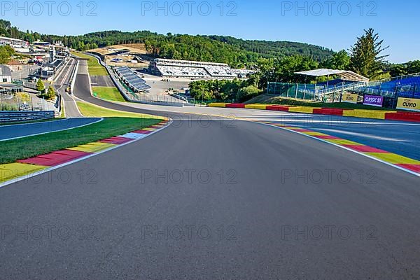 View from the centre of the racetrack to the 40-metre-high hilltop above the steep Raidillon ramp in front and the dangerous Eau Rouge bend behind it on the Spa Francorchamps racetrack without racing cars
