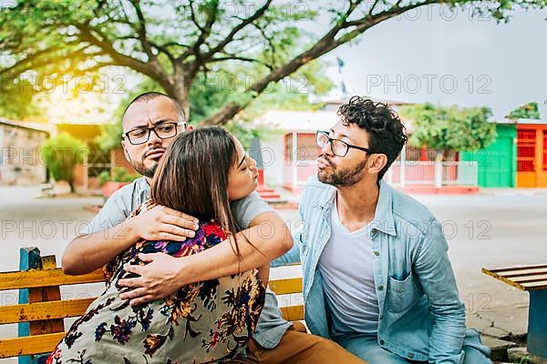 Unfaithful girlfriend hugging her boyfriend in a park secretly kissing another man. Couple infidelity concept