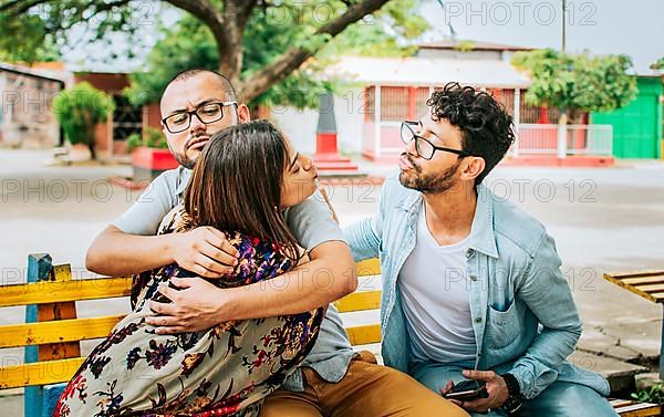 Disloyal girlfriend hugging her boyfriend in a park secretly kissing another man. Couple infidelity concept