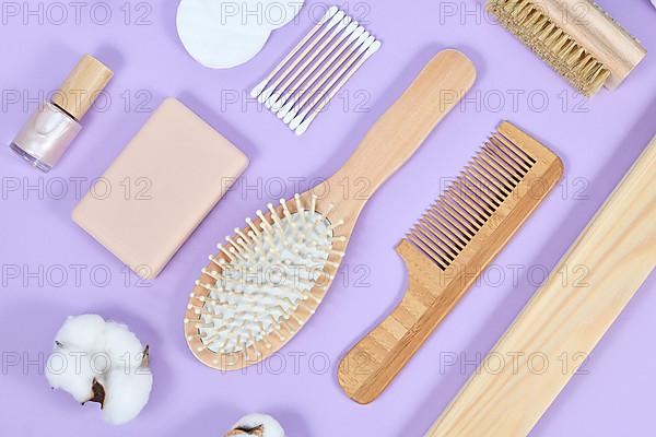 Eco friendly wooden beauty and hygiene items like comb and soap on purple background