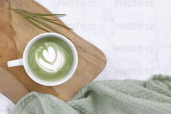 Cup with green tea latte on wooden board