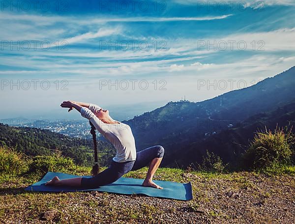 Vintage retro effect hipster style image of sporty fit woman practices yoga Anjaneyasana