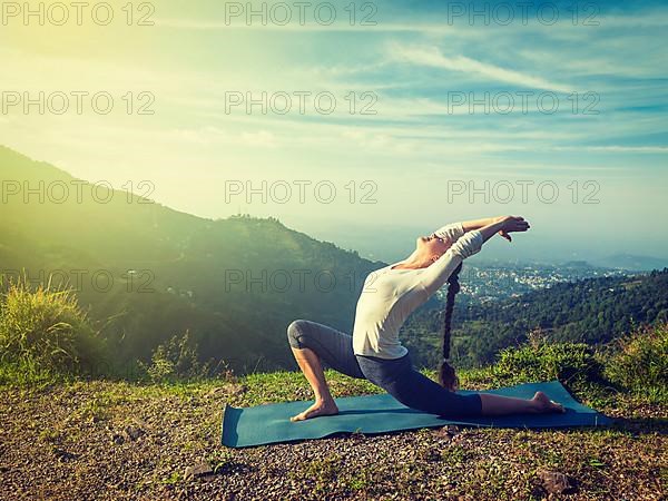 Vintage retro effect hipster style image of sporty fit woman practices yoga Anjaneyasana
